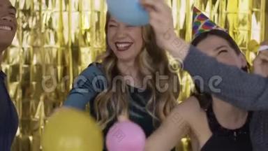 在一个聚会上，快乐的人戴着纸节日的帽子打气球。 一群笑的混血儿在
